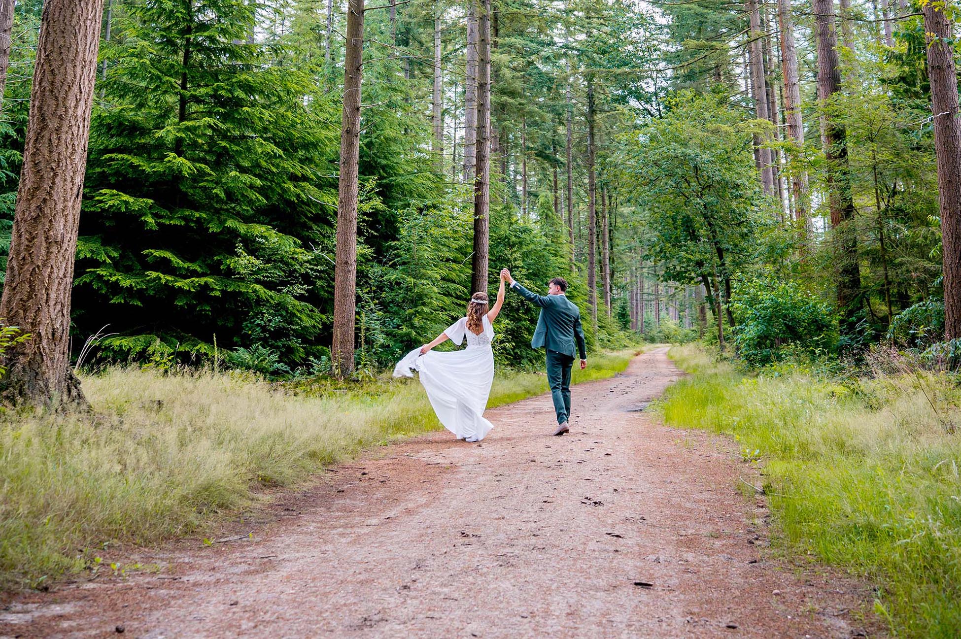 Bruidsfotograaf fotografeert vrolijk bruidspaar in een mooi bos