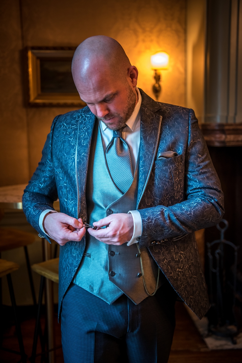 Stoere bruidegom kleedt zich aan in Kasteel Wijenburg in Echteld