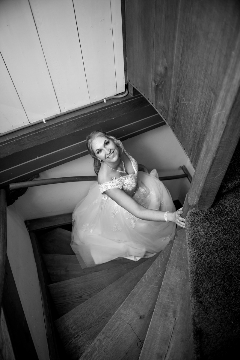 Mooie bruid in witte jurk loopt op een trap in Kasteel Wijenburg in Echteld