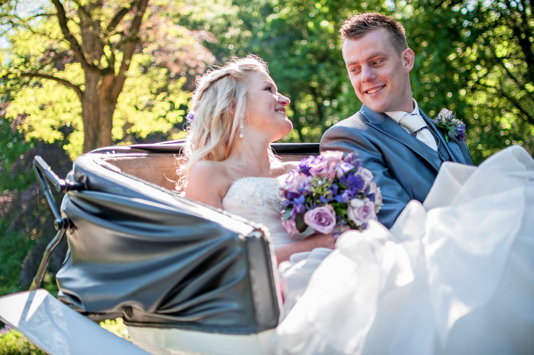 bruidspaar in open koets kijkt elkaar verliefd aan gefotografeerd door trouwfotograaf in Hengelo