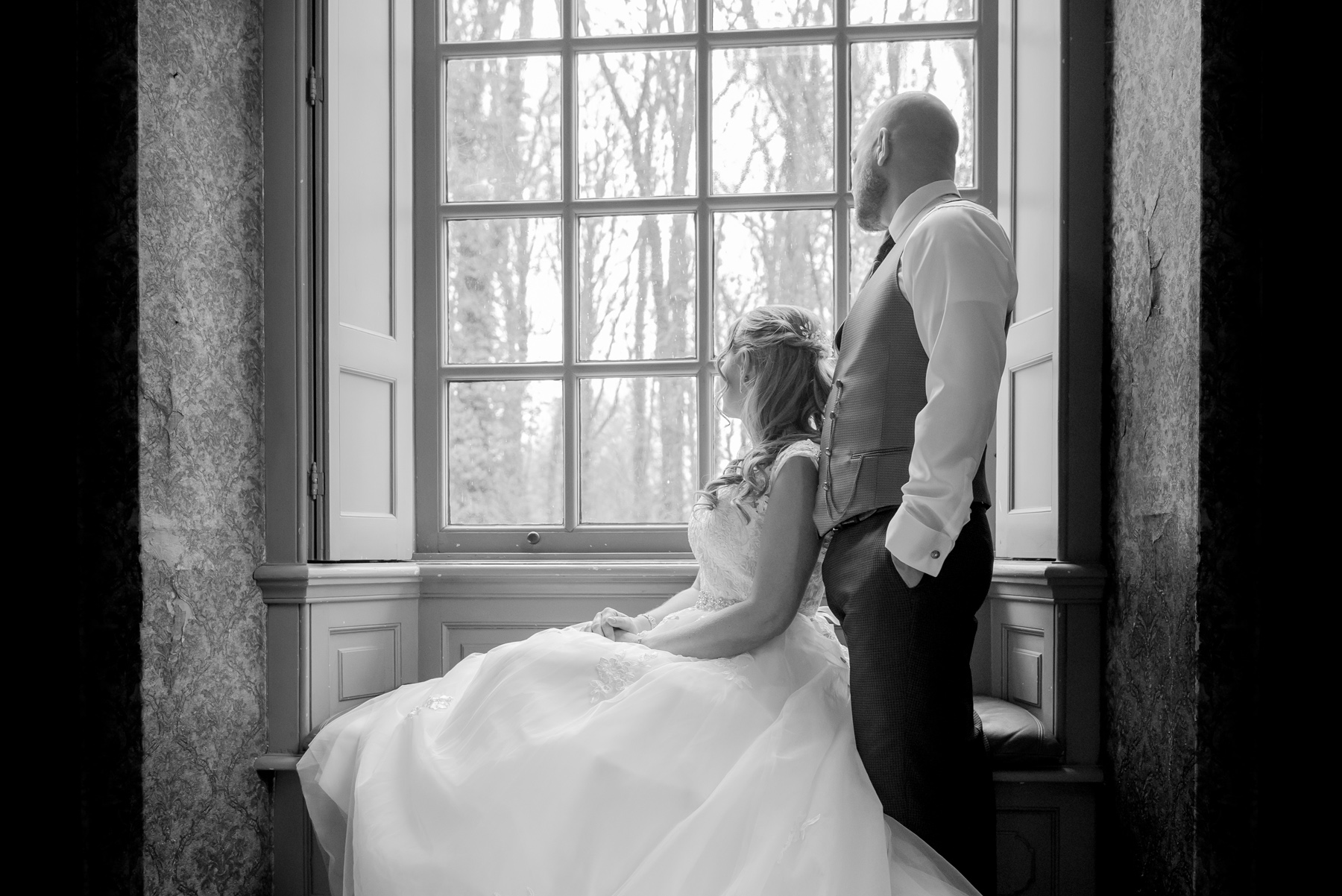 Bruid en bruidegom staan voor een groot raam gefotografeerd door trouwfotograaf Novo Fotografie in trouwlocatie Landgoed Huis De Voorst