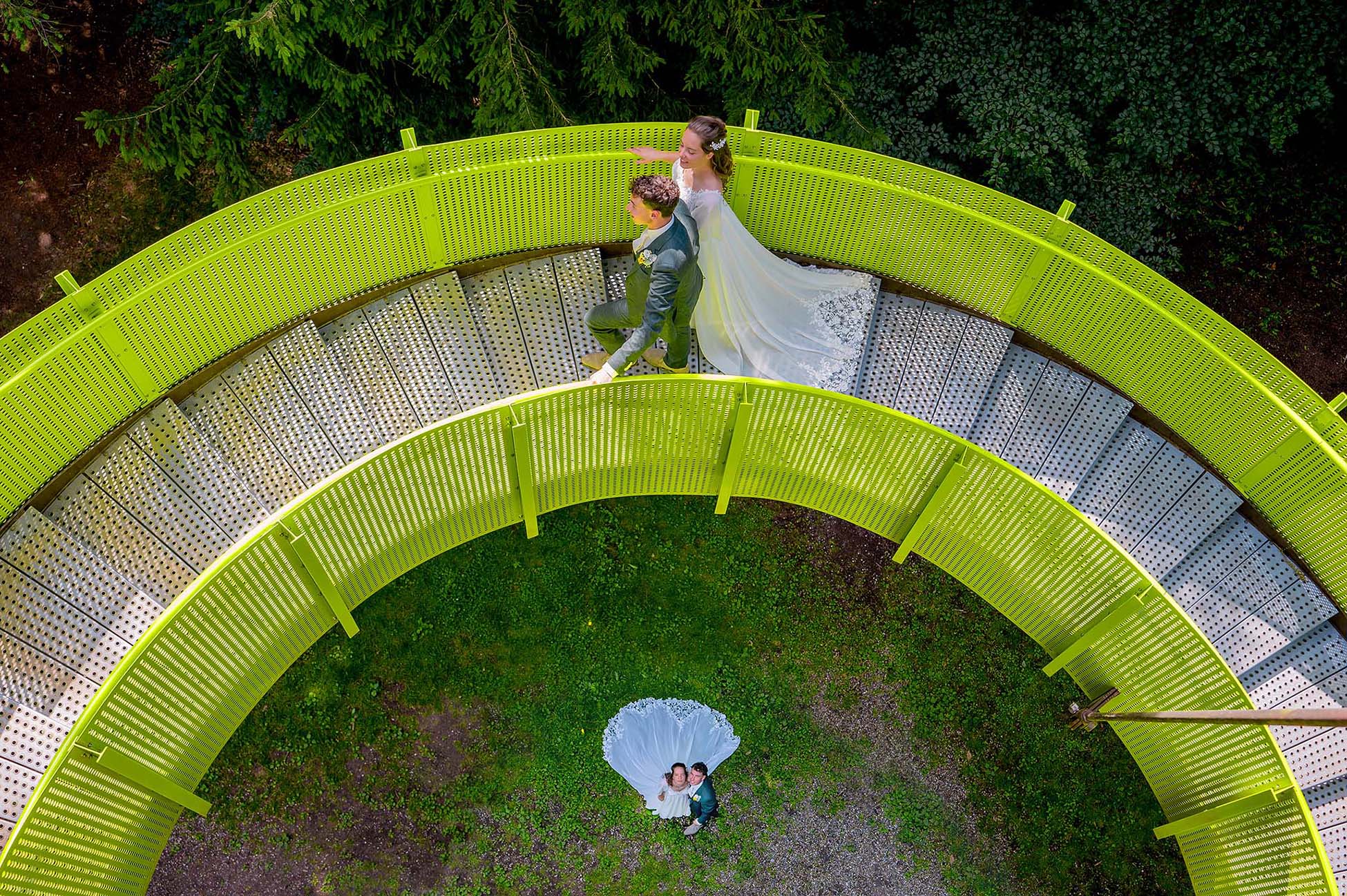 Bruidspaar loopt op een groene trap van een hoge uitkijktoren - foto gemaakt door jullie trouwfotograaf